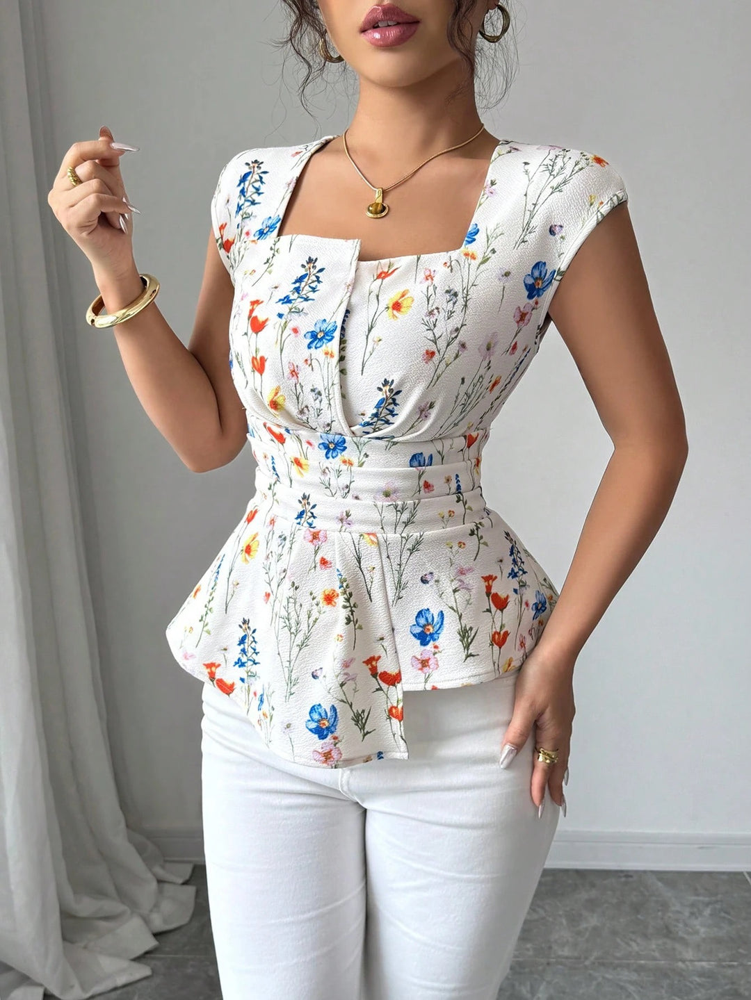 Damebluse med tætsiddende peplum-silhuet og blomsterdesign Stilla