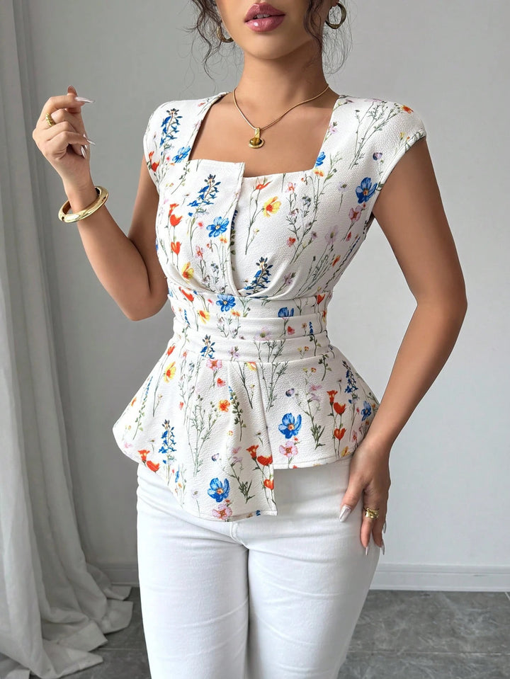 Damebluse med tætsiddende peplum-silhuet og blomsterdesign Stilla