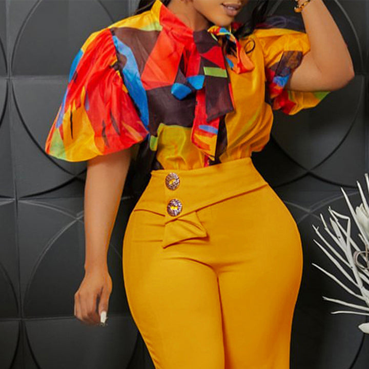 Damebluse med dekorativ sløjfekrave og livligt mønster Stilla