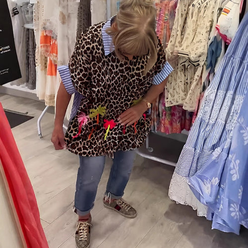 Dame med vidt skårne poncho-tunika med leopardprint og dekorative flamingo-applikationer Skovae。