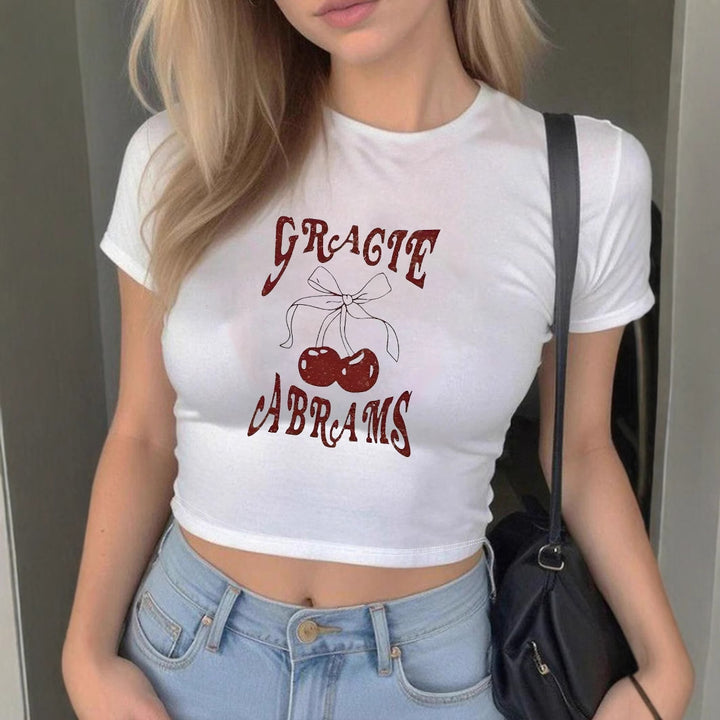 Dame Crop-T-Shirt med muntert kirsebærmønster og legende skrift Skovae