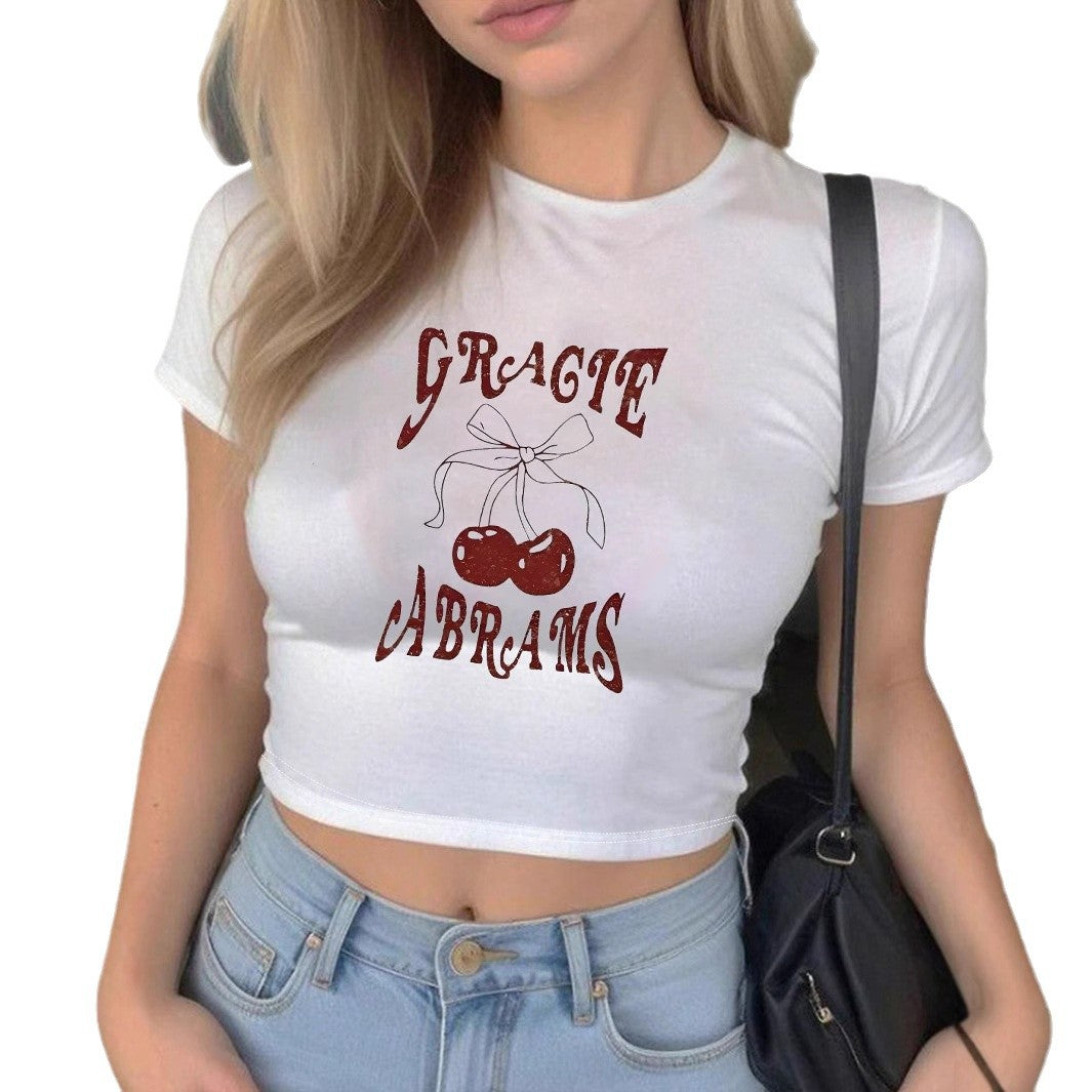 Dame Crop-T-Shirt med muntert kirsebærmønster og legende skrift Skovae