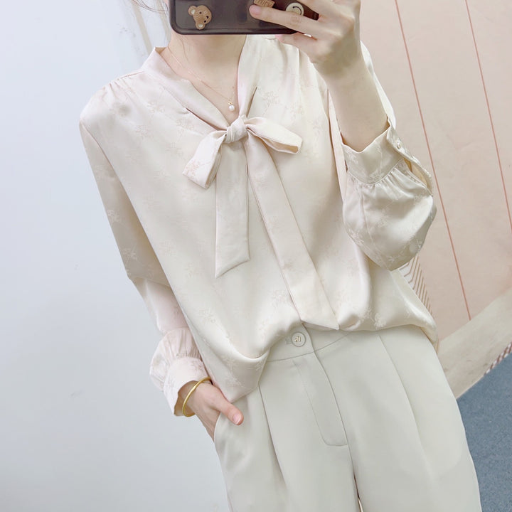 Damebluse med elegant sløjfe og floralt mønster Stilla