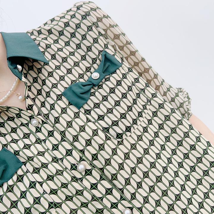Damebluse med modeprint og elegante sløjfeapplikationer Stilla