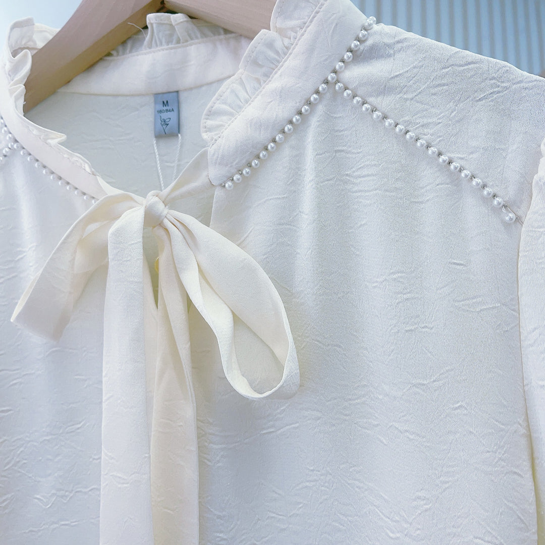 Damebluse med flæsedetaljer og elegant sløjfe Stilla