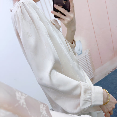 Damebluse med elegant sløjfe og floralt mønster Stilla