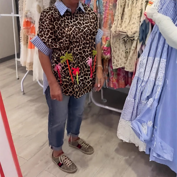 Dame med vidt skårne poncho-tunika med leopardprint og dekorative flamingo-applikationer Skovae。